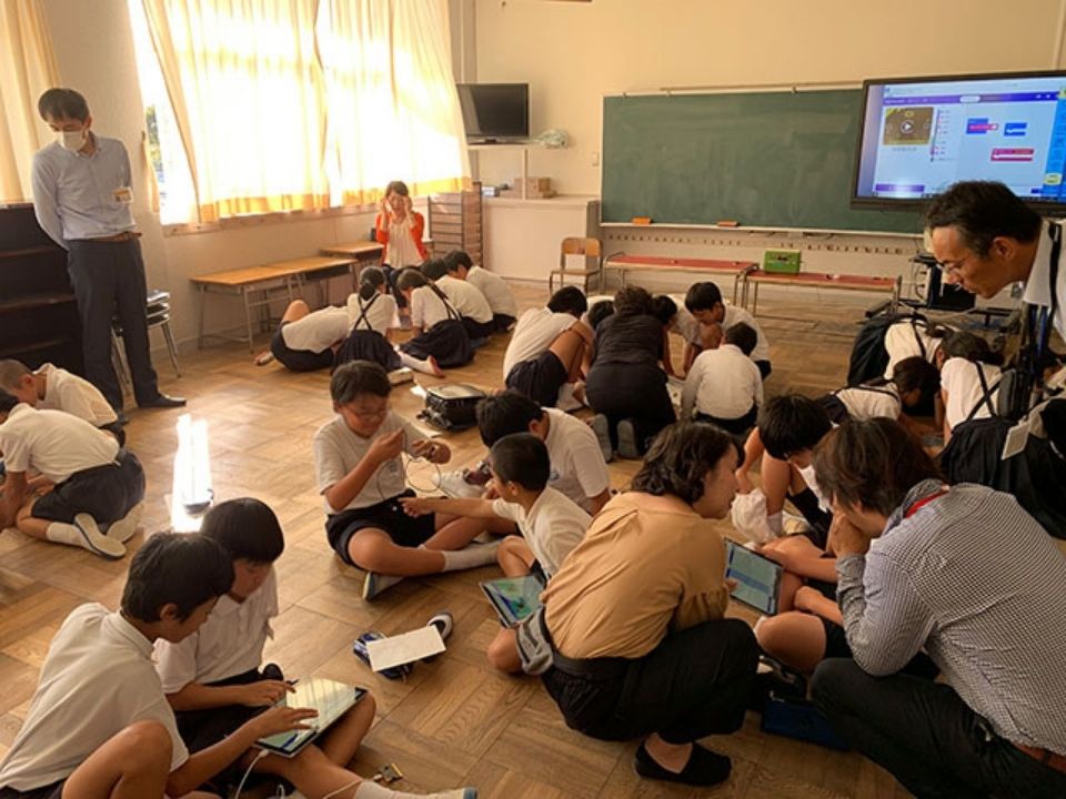 教室の床に輪になって座り取り組んでいる生徒たち